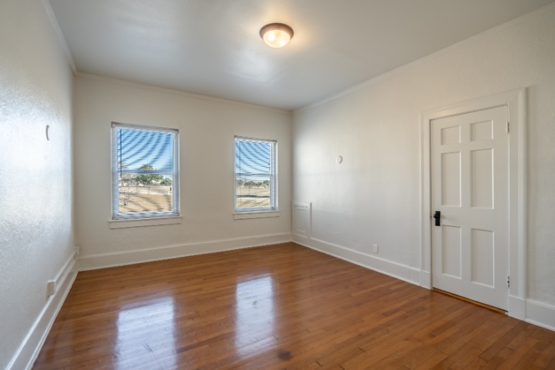 Home bedroom with hardwood flooring and two windows